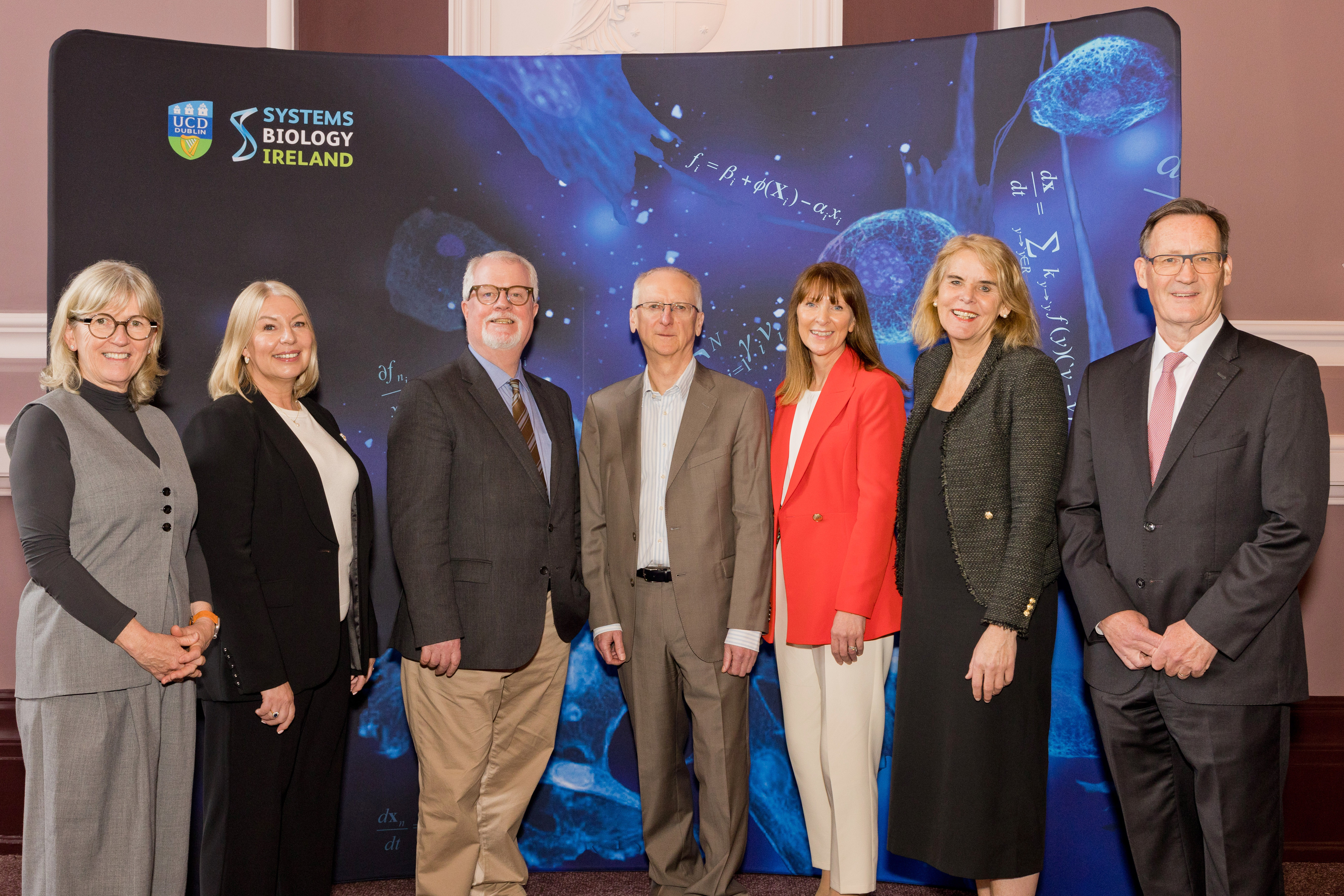 a group of adults in front of a blue banner